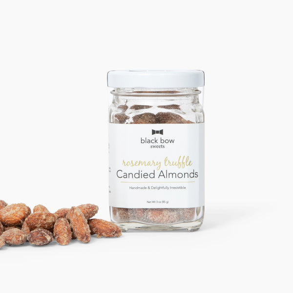 A jar of Black Bow Sweets candied rosemary truffle coated almonds next to a small pile of almonds.
