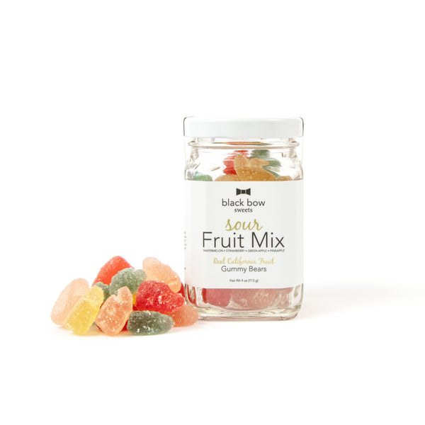 A jar of Black Bow Sweets sour fruit mix gummy bears next to a small pile of gummy bears.