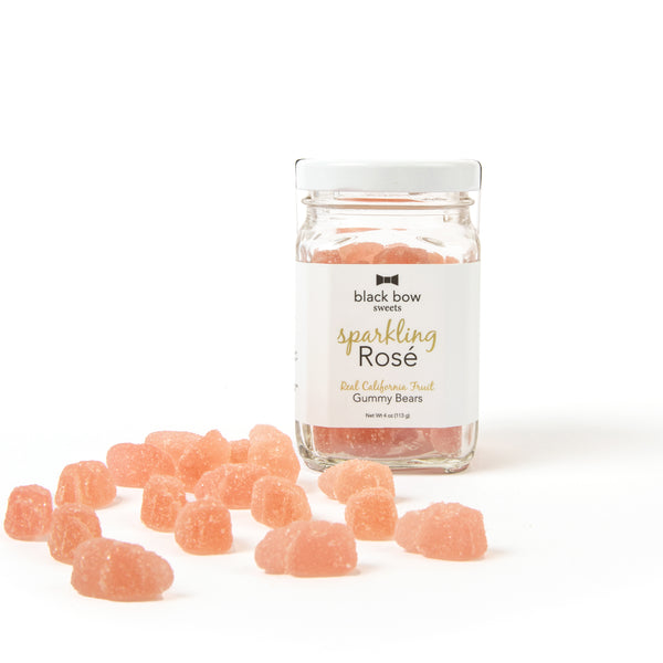 A jar of Black Bow Sweets sparkling rosé gummy bears next to loose gummy bears.