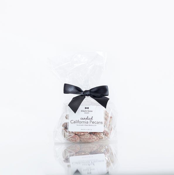 A bag of Black Bow Sweets candied California cinnamon and sugar coated pecans tied with a black bow.