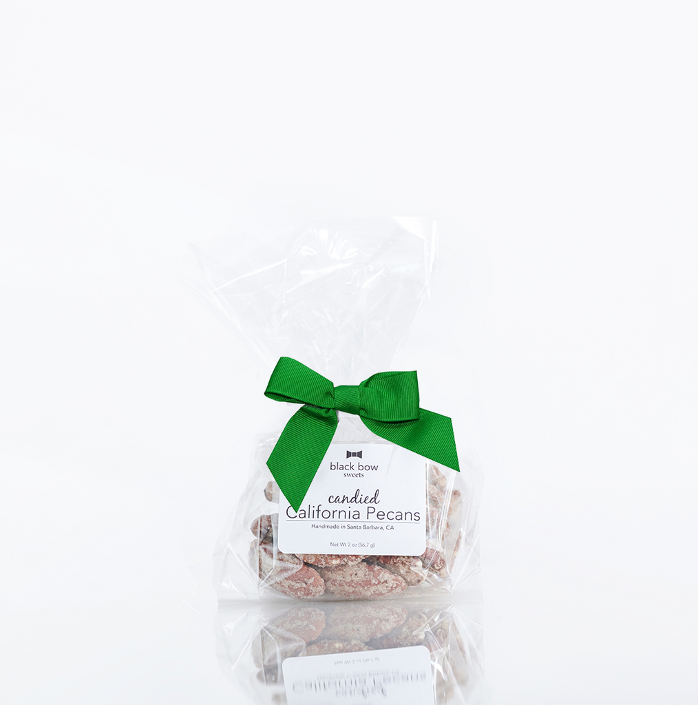 A bag of Black Bow Sweets candied California cinnamon and sugar coated pecans tied with a green bow.