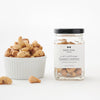 A jar of Black Bow Sweets sea salt and cracked black pepper toasted cashews next to a white bowl filled with the cashews.