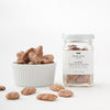 A jar of Black Bow Sweets candied California cinnamon and sugar coated pecans next to a white bowl filled with the pecans.