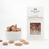 A box of Black Bow Sweets candied California cinnamon and sugar coated pecans next to a white bowl filled with the pecans.