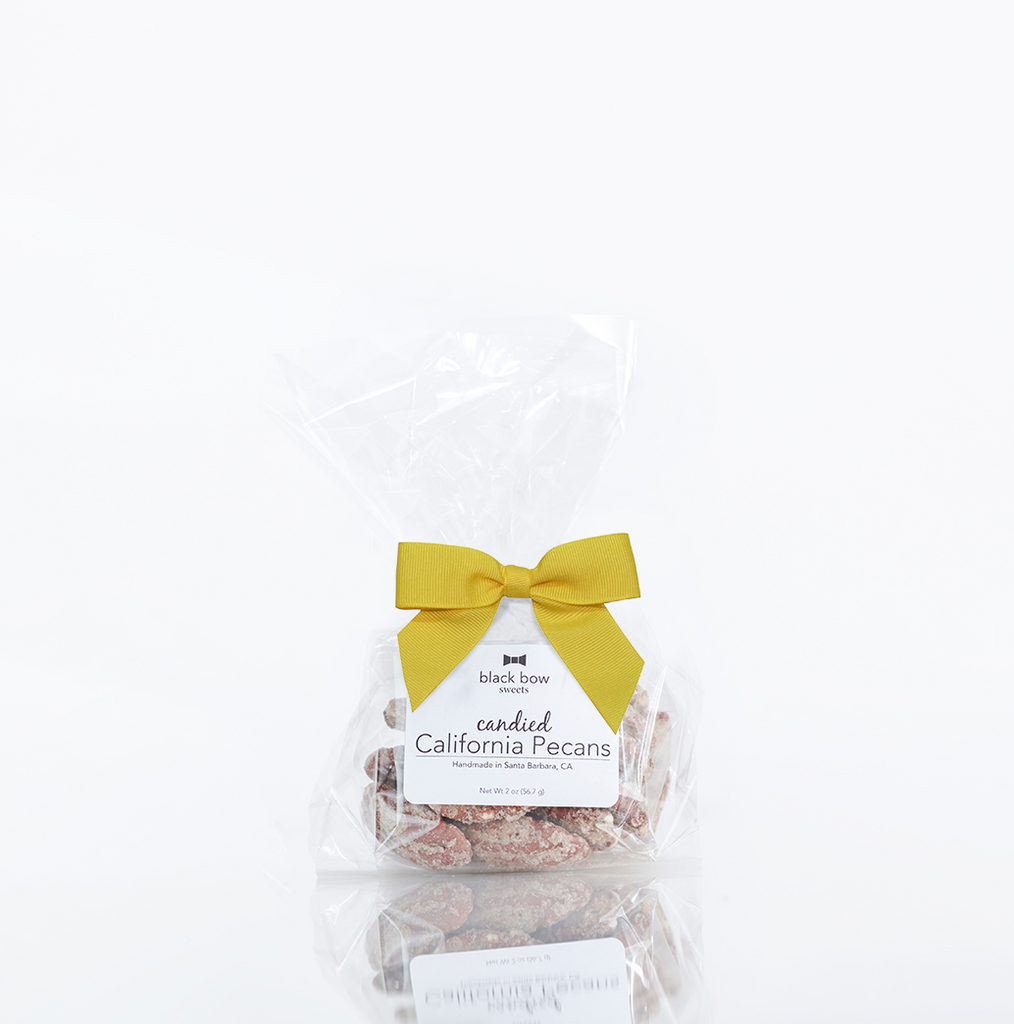 A bag of Black Bow Sweets candied California cinnamon and sugar coated pecans tied with a yellow bow.