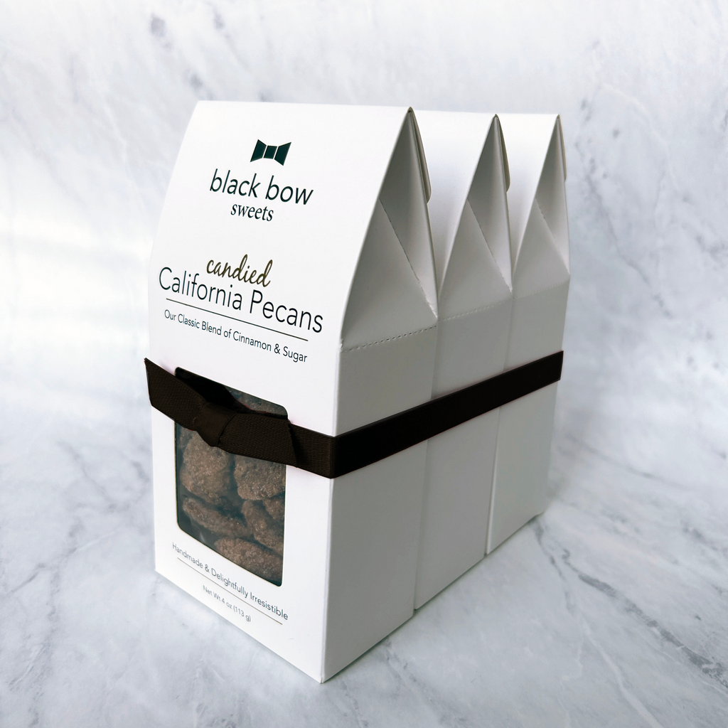 Boxes of Black Bow Sweets candied California cinnamon and sugar coated pecans, almonds, and walnuts tied together with a black bow.