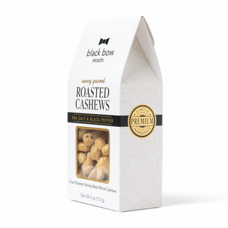 A white stand-up box of Black Bow Sweets Savory Gourmet Roasted Cashews, Sea Salt & Black Pepper flavor, with a clear window showing the cashews inside and a gold premium seal.