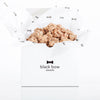 A white Black Bow Sweets gift box filled with candied California cinnamon and sugar coated walnuts loosely wrapped in white tissue paper with small black bows.