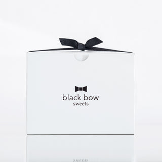 A white Black Bow Sweets gift box tied with a black bow.