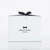 A white Black Bow Sweets gift box tied with a black bow.