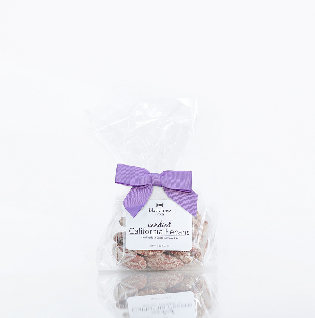 A bag of Black Bow Sweets candied California cinnamon and sugar coated pecans tied with an orchid bow.