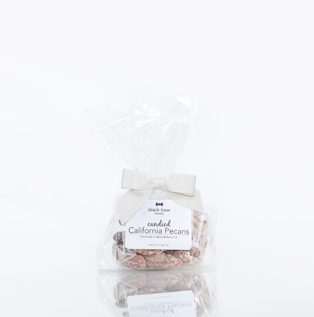 A bag of Black Bow Sweets candied California cinnamon and sugar coated pecans tied with a white bow.